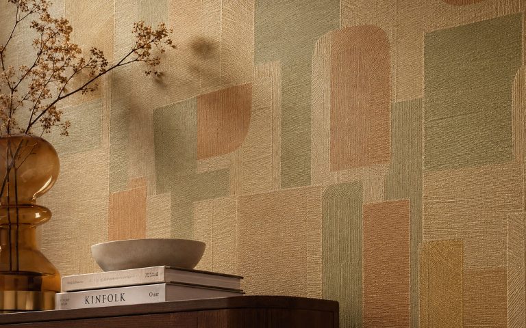 Detailaufnahme einer strukturierten Design-Tapete mit geometrischem Muster in warmen Beige-, Grün- und Terracottatönen. Das Bild vermittelt moderne Wandgestaltung, hochwertige Materialien und ein edles Wohnambiente.